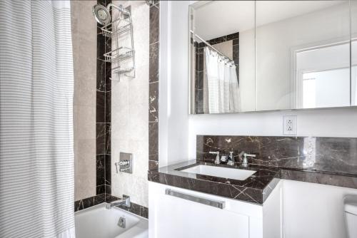 a bathroom with a sink and a mirror and a tub at Back Bay 1BR w WD Gym Roof nr Copley Sq BOS-751 in Boston