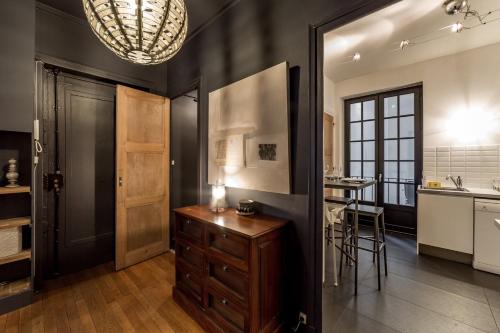 - une cuisine avec des murs noirs, une armoire en bois et une table dans l'établissement Place Des Jacobins/Appartement 4 Personnes AIL, à Lyon