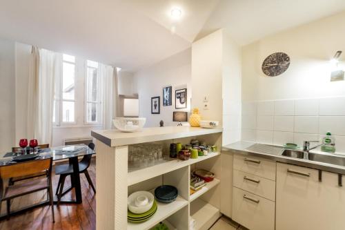 - une cuisine avec des placards blancs, un évier et une table dans l'établissement Un havre de paix au cœur de Lyon AIL, à Lyon