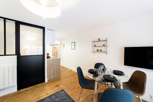 une salle à manger avec une table et des chaises et une télévision dans l'établissement Appartement au cœur du 6ème arrondissement AIL, à Lyon