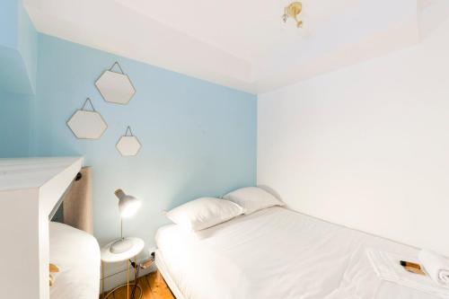 - une chambre avec un lit blanc et des murs bleus dans l'établissement Appartement au cœur du 6ème arrondissement AIL, à Lyon