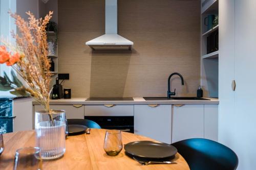 - une cuisine avec une table en bois, des chaises et un évier dans l'établissement La Balnéo des Terreaux AIL, à Lyon