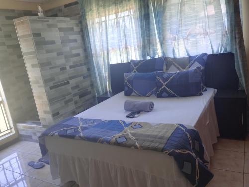 ZeerustにあるCOMFORT ZONE GUEST HOUSEの青いシーツと枕が備わったベッドのある寝室