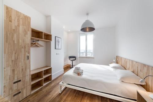 a bedroom with a large white bed and wooden cabinets at Brand new apartment 2022 Lyon Part-Dieu AIL in Lyon