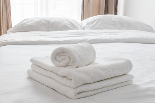 una pila de toallas blancas en una cama en Borkowska Comfort Apartment en Cracovia