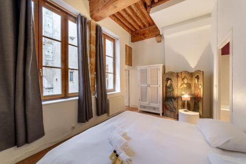 um quarto com uma grande cama branca e janelas em The Lawyers' Lodge of Old Lyon em Lyon