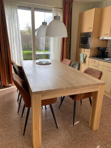 uma mesa de jantar em madeira com cadeiras numa cozinha em Heerlijk genieten. em Hoogersmilde