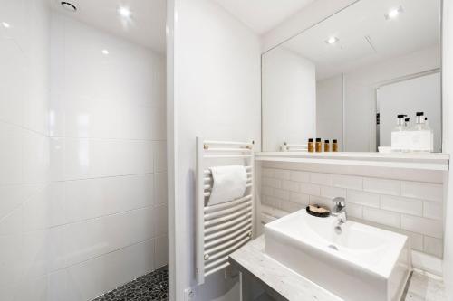 une salle de bain blanche avec un lavabo et un miroir dans l'établissement Authentique studio au coeur du Vieux Lyon AIL, à Lyon