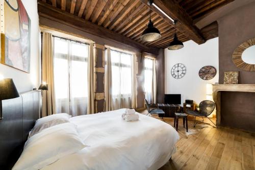 - une chambre avec un grand lit blanc et une cheminée dans l'établissement Authentique studio au coeur du Vieux Lyon AIL, à Lyon