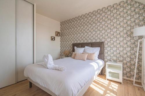 um quarto com uma grande cama branca e papel de parede floral em DISNEYLAND - WIFI - PARKING - CENTRE VILLE em Bailly-Romainvilliers
