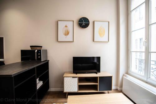 uma sala de estar com uma televisão, uma secretária e um relógio em Jacobin Temple Studio in the heart of Lyon AIL em Lyon