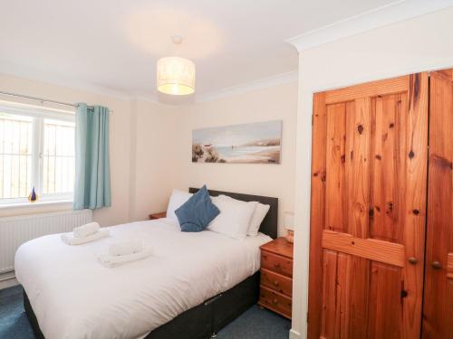 a bedroom with a large white bed with a wooden cabinet at Garland in Weymouth