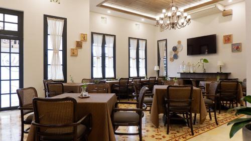une salle à manger avec des tables et des chaises ainsi qu'un lustre dans l'établissement The Margaux Hotel Yogyakarta, à Yogyakarta