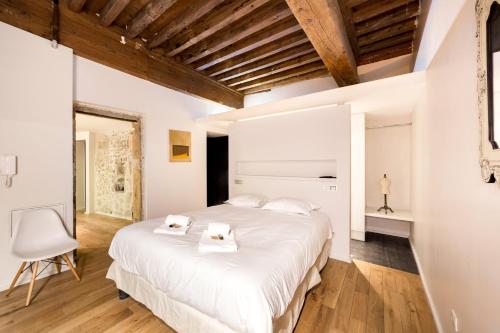 une chambre avec un grand lit blanc et une chaise dans l'établissement La suite Bibliothèque - Quartier historique AIL, à Lyon