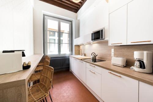 une cuisine avec des placards blancs et une grande fenêtre dans l'établissement Spacious and cozy in Vieux Lyon AIL, à Lyon