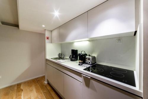 une cuisine avec des armoires blanches et un four à plaques de cuisson dans l'établissement Le Duplex du Change - Lyon AIL, à Lyon