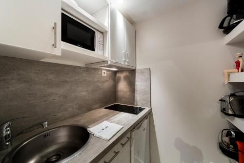 a kitchen with a sink and a microwave at Le Petit Change - Fully equipped studio in Lyon in Lyon