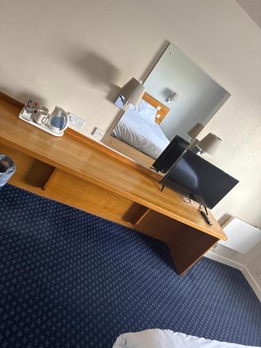 a bedroom with a bed and a desk with a mirror at Thurrock Hotel M25 Services in Aveley