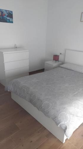 um quarto com uma cama branca e uma cómoda em Apartamento La Mar em Carboneras