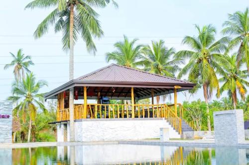 a pavilion next to a pool with palm trees at Liverpool Estate - Chilaw in Chilaw