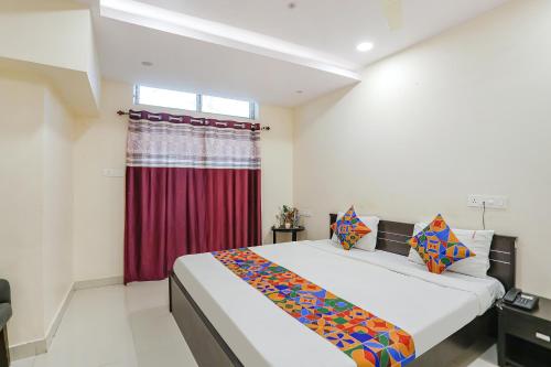 a bedroom with a large bed with a red curtain at FabExpress Girija Inn in Nagpur