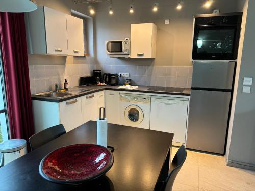 La cuisine est équipée d'une table, d'un évier et d'un lave-vaisselle. dans l'établissement ღ Maison Orion - T3 Spacieux, Jardin et proche mer, à Sainte-Marie de Ré