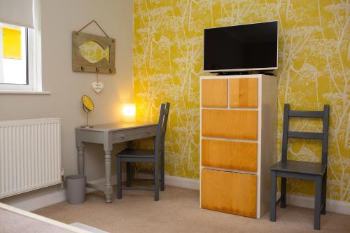 a room with a desk and a tv on a wall at Tryweryn Cottage Saundersfoot in Saundersfoot
