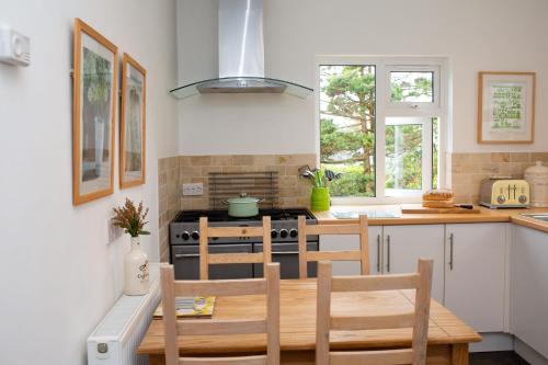 a kitchen with a table and chairs and a stove at Tryweryn Cottage Saundersfoot in Saundersfoot