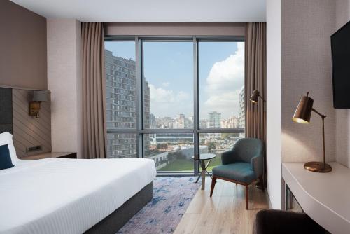 イスタンブールにあるDelta Hotels by Marriott Istanbul Kagithaneのベッドと大きな窓が備わるホテルルームです。