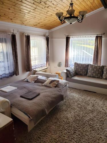 um quarto com uma cama grande e um sofá em Szilvásváradi Kemencés Apartmanok em Szilvásvárad