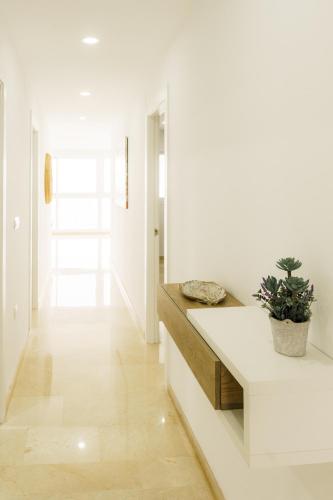 a white hallway with a potted plant on a bench at Santa Margarita - Benisun in Benidorm