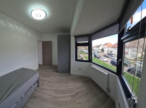 een slaapkamer met 2 grote ramen en een bed erin bij Remarkable 3-Bed Apartment in London in Hendon