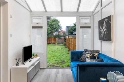 a living room with a blue couch and a tv at Modern 2 Bedroom APT 3 min walk to Tube station in London