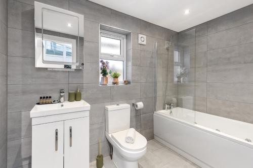 a bathroom with a toilet and a tub and a sink at Modern 2 Bedroom APT 3 min walk to Tube station in London