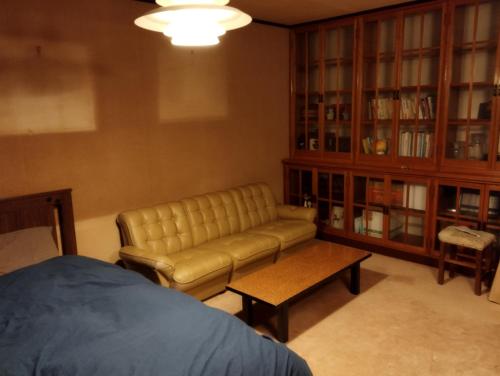un soggiorno con divano e libreria di ゲストハウスかもめ a Ishinomaki