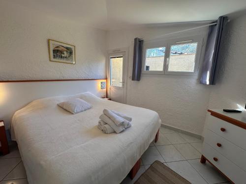 een slaapkamer met een wit bed en handdoeken bij LBV Les Bastidons de Villepey in Saint-Aygulf