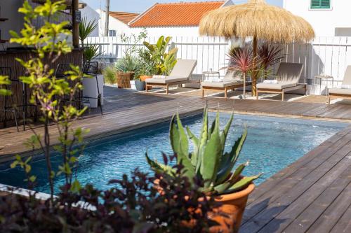 una piscina con terraza, sillas y plantas en Casa Idalia Boutique Hotel, en Comporta