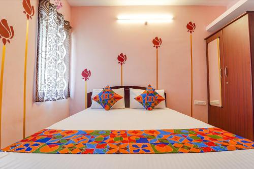 um quarto com uma cama com um edredão colorido em FabExpress Sparrow Fern Palace em Ooty