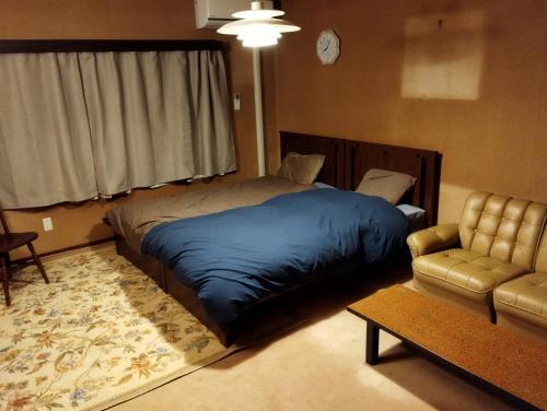 una camera con letto, divano e sedia di ゲストハウスかもめ a Ishinomaki