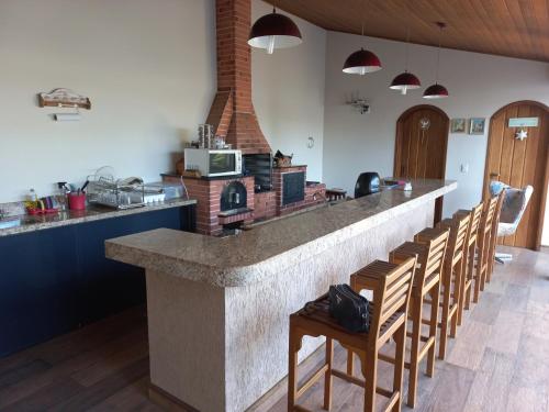 a kitchen with a counter with a row of chairs at Hospedagem Aconchegante in Espirito Santo Do Pinhal