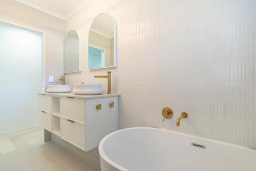 a white bathroom with a tub and a sink at New Lux Apt opposite Buddina patrolled Beach in Buddina