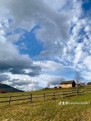 a field with a wooden fence and a barn at Байка Карпат in Vorokhta