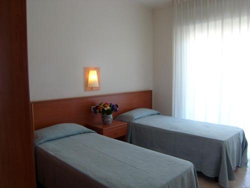 two beds in a hotel room with a window at Residence Torre Del Mar in Alba Adriatica