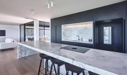 a kitchen with a large marble counter and stools at ONYX HOUSE - Wainui Beach in Gisborne