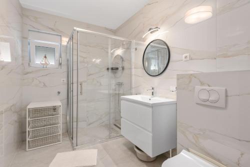 a white bathroom with a shower and a sink at Apartment ANTONIJA in Rogoznica
