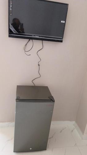 einen Flachbild-TV an einer Wand über einem Kühlschrank in der Unterkunft الشوبك نجل in Nijil