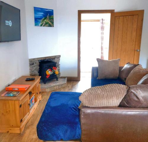 a living room with a couch and a fireplace at Heart of Kernow Holidays in Bugle