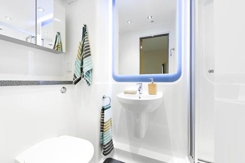 een witte badkamer met een wastafel en een spiegel bij For Students Only Premium Studios and Private Ensuite Rooms at John Bell House in Belfast in Belfast