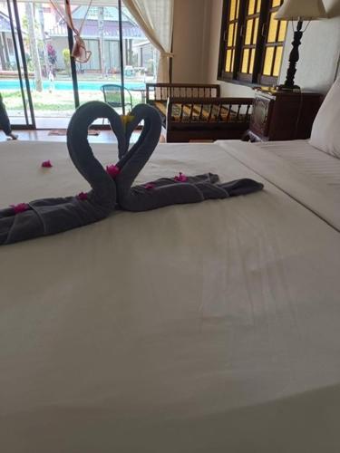 two towel swans sitting on top of a bed at ไอยรารีสอร์ต in Ban Map Khangkhao