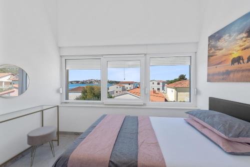 a white bedroom with a bed and two windows at Apartment ANTONIJA in Rogoznica